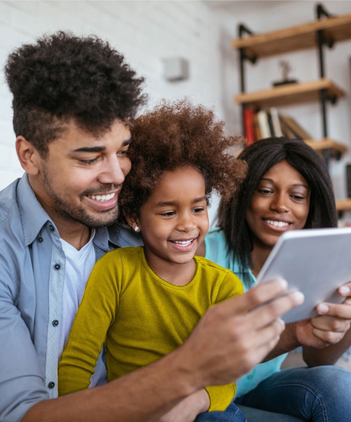 A family looking at a tablet learning about internet safety for kids.