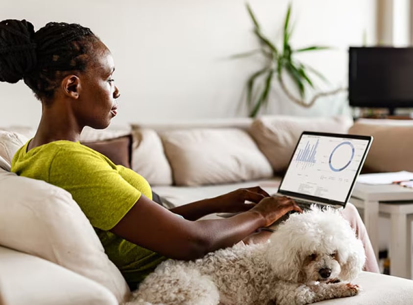 Seated woman with dog working on laptop
